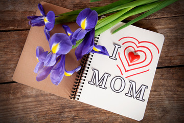 Notebook decorated for mother's day and flowers on wooden background