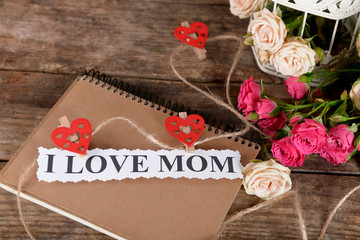Notebook for mother's day and flowers on wooden background