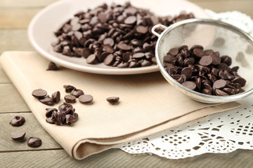 Chocolate morsels on plate, on wooden board
