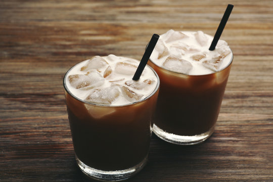 Two cups of ice coffee with straw on wooden background