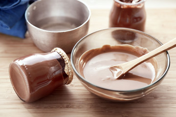 Melted chocolate on glass bowl  tray, on wooden background