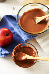 Melted chocolate on glass bowl, on wooden background