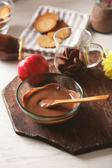Melted chocolate in glass bowl, on wooden background