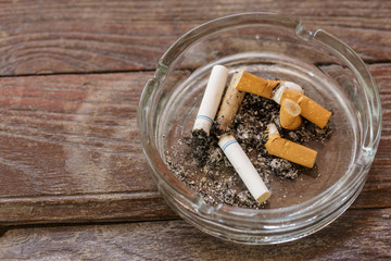 Closeup view of full ashtray on the wood  table