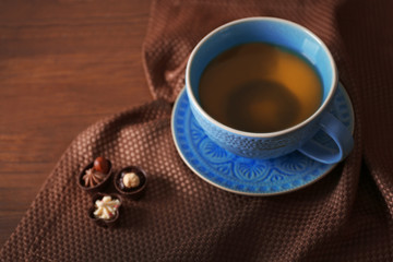 Cup of tea with autumn decor on wooden table.