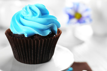 Delicious chocolate cupcake with blue cream on served table, close up