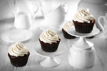 Delicious chocolate cupcakes with cream in a row on served table, close up