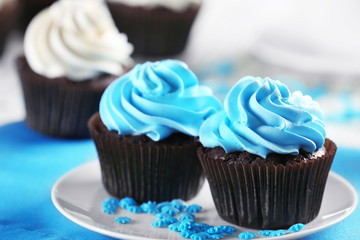 Delicious chocolate cupcakes with blue cream on decorated wooden  table, close up