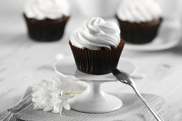 Delicious chocolate cupcake with cream on served table, close up