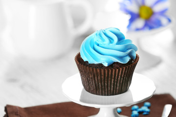 Delicious chocolate cupcake with blue cream on served table, close up