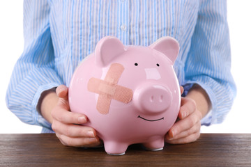 Woman holding Piggy Bank with adhesive bandage, on white background