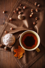 Cup of tea with autumn decor on wooden table.
