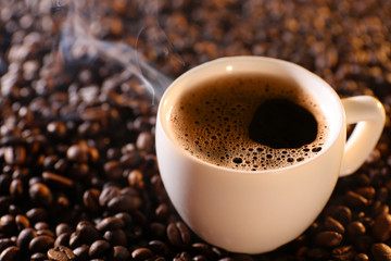 Cup of hot coffee on coffee beans background