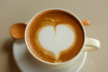 Heart shape in hot cappuccino coffee cup on white desk