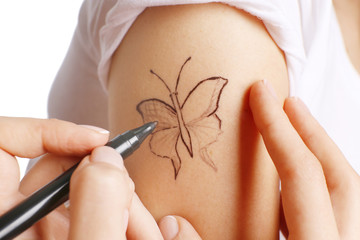 Woman painting tattoo on a shoulder