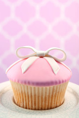 Tasty cupcake with bow on bright background