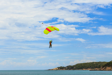 Parachutist coming down the seaside