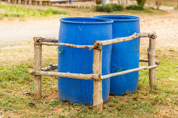 Two Blue Trash bins  in wooden fence