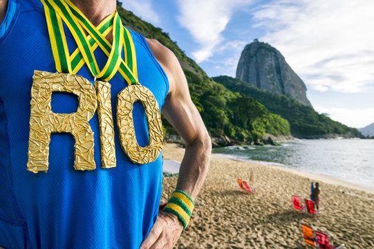 Athlete wearing gold RIO medals standing outdoors in front of Sugarloaf Mountain in Rio de Janeiro, Brazil during golden morning sunrise