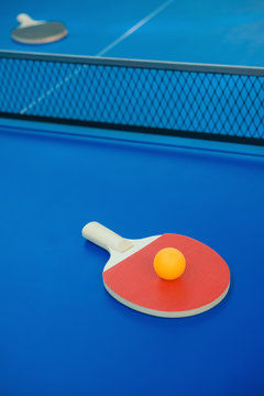 pingpong racket and ball and net on a blue pingpong table vertical