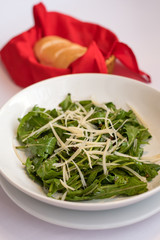 rocket salad with parmesan cheese served with bread in red basket