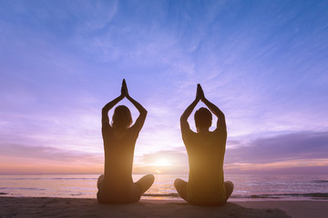 Two young adult doing a yoga training at the beach during sunset