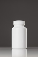 white plastic bottle of supplements on gray background