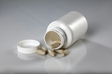 white plastic bottle of supplements and pills beside it