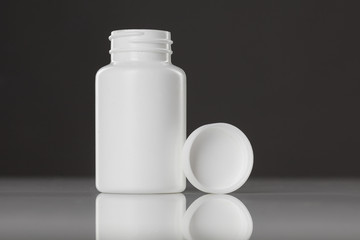white plastic bottle of supplements on gray background