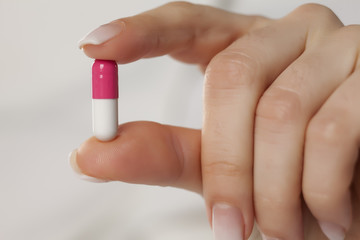 female hand holding a capsule with her fingers