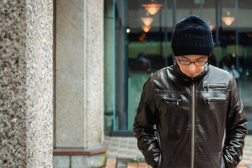 Fototapeta na wymiar An Asian Man in a Brown Jacket is walks in a Street