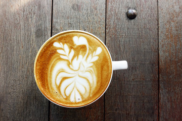 cup of latte art coffee on wooden background