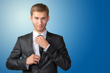 Young handsome businessman adjusting his tie
