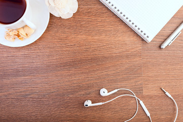 cup of hot coffee, headphones, notebook, pen and dried flowers on a wooden background. Place for text. Square image.