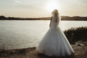 Fototapeta na wymiar gorgeous stylish elegant happy blonde bride looking at the sunset