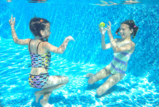 Children swim in pool or sea underwater, happy active girls have fun under water
