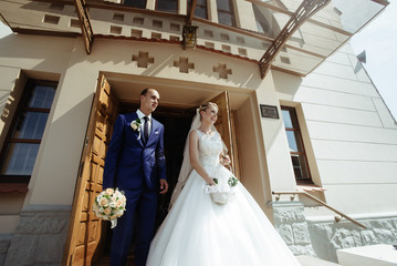 newlyweds elegant handsome groom and beautiful stylish happy blonde bride at the church