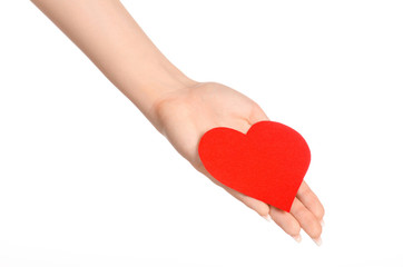 Love and greetings card theme: beautiful female hand holding a paper card red heart isolated on a white background in studio