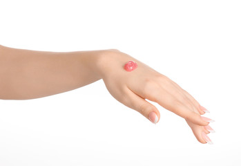 Health and body care theme: beautiful female hand with pink scrub cream on a white background isolated