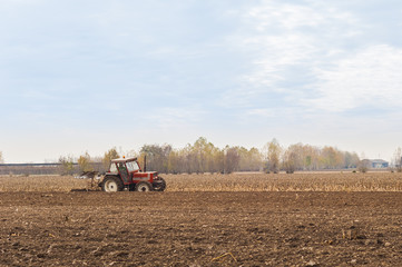 Obraz premium Red Tractor Plowing in Autumn