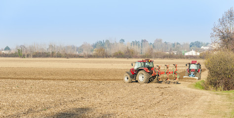 Obraz premium Red Tractor Plowing in Autumn.
