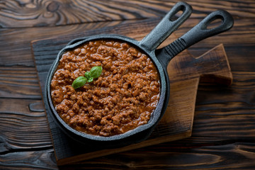 Frying pan with bolognese sauce on a rustic wooden background