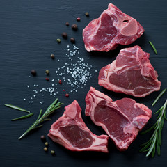 Raw T-bone lamb steaks with seasonings, close-up, top view