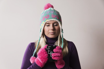 woman wearing a knitted cap holding a cup with closed eyes