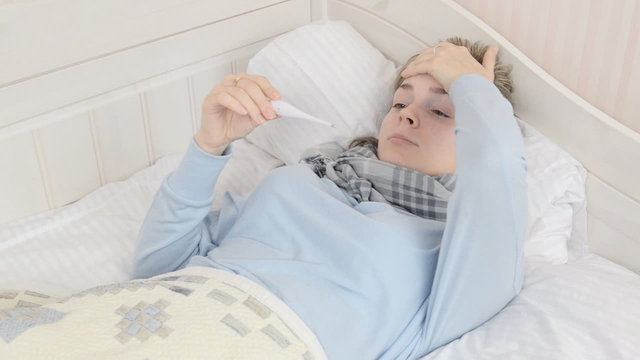 Sick woman uses a thermometr.