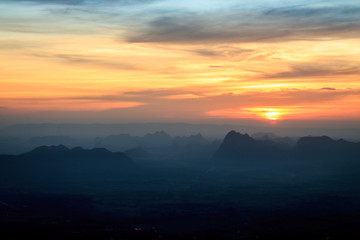 Sunset landscape orange sky and silhouette mountain with fog at