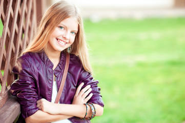 Happy teenage girl 12-15 year old posing outdoors over green nature background. Looking at camera. Childhood.