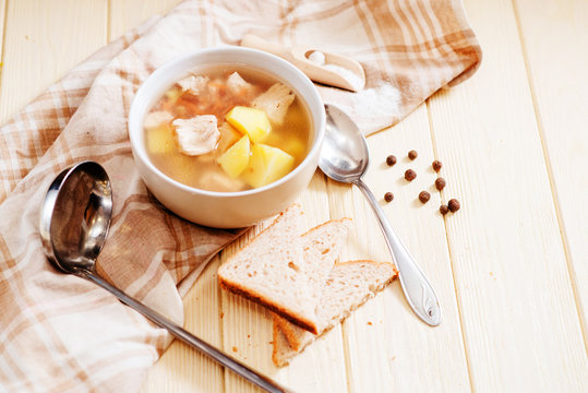 healthy hot lunch , chicken soup with potatoes , carrots , chicken breast , spices and rye bread on a wooden background