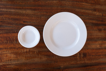Empty white plate and small chalice on wooden background