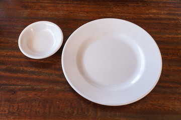 Empty white plate and small chalice on wooden background